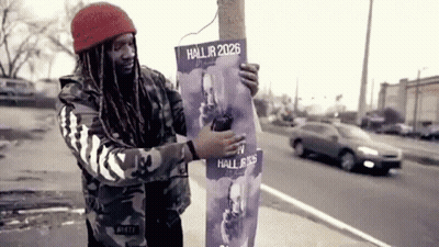 A Man Is Holding A Poster That Says Hall Jr 2026 GIF