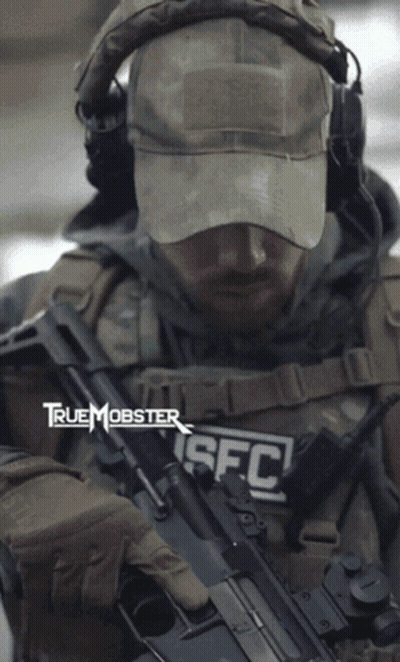 A Man Is Holding A Rifle With The Letters Sfc On His Chest GIF