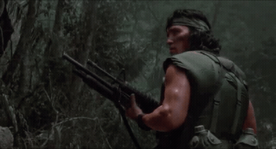 A Man Is Holding A Shotgun In The Woods GIF