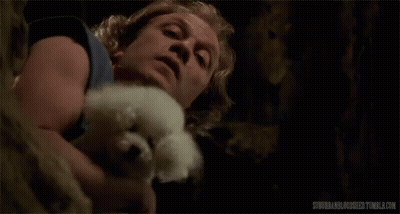 A Man Is Holding A Small White Dog In His Arms And Licking It . GIF