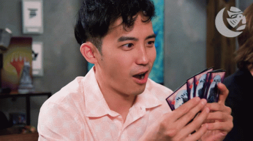 A Man Is Holding A Stack Of Magic Cards In His Hands GIF
