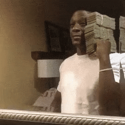 A Man Is Holding A Stack Of Money In His Hand In Front Of A Mirror . GIF