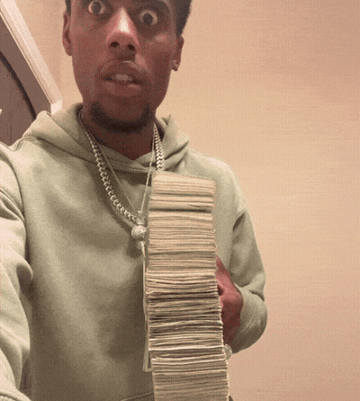 A Man Is Holding A Stack Of Money In His Hand GIF