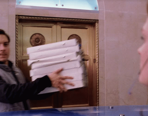 A Man Is Holding A Stack Of Pizza Boxes GIF
