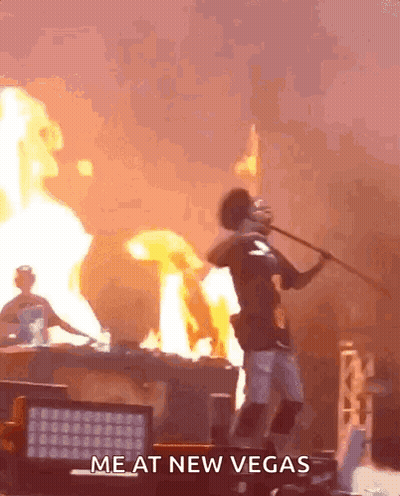 A Man Is Holding A Stick In Front Of A Fire With The Words Me At New Vegas Written On The Bottom GIF