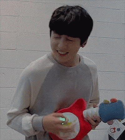 A Man Is Holding A Stuffed Animal In His Hands And Smiling GIF