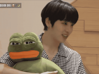 A Man Is Holding A Stuffed Frog With A Yellow Beak GIF