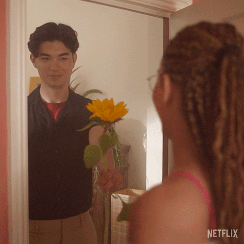 A Man Is Holding A Sunflower In Front Of A Mirror With A Netflix Logo On The Bottom GIF
