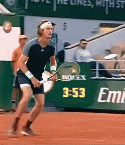 A Man Is Holding A Tennis Racket In Front Of A Sign That Says Emirates GIF