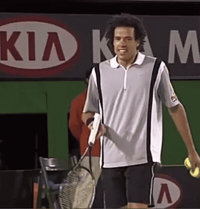 A Man Is Holding A Tennis Racquet And A Tennis Ball In Front Of A Kia Sign GIF