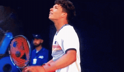 A Man Is Holding A Tennis Racquet And Looking Up GIF