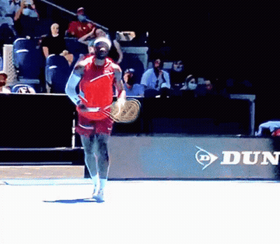 A Man Is Holding A Tennis Racquet In Front Of A Dunlop Ad GIF