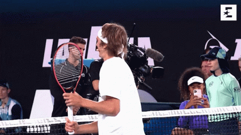 A Man Is Holding A Tennis Racquet In Front Of A Kia Advertisement GIF