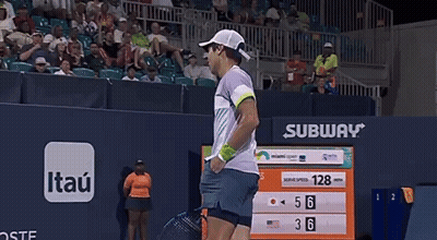A Man Is Holding A Tennis Racquet In Front Of A Scoreboard With Subway Written On It GIF