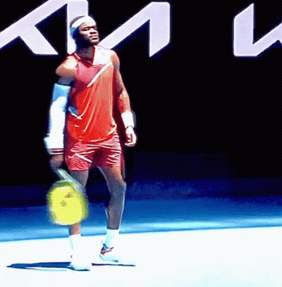 A Man Is Holding A Tennis Racquet In Front Of A Sign That Says Km GIF