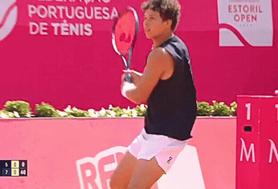 a man is holding a tennis racquet in front of an advertisement for the portuguesa de tenis