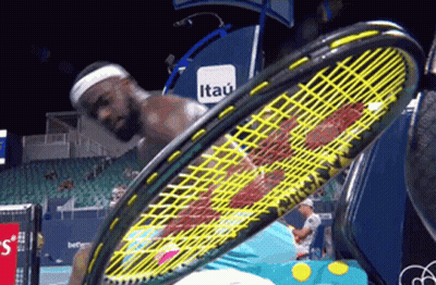 A Man Is Holding A Tennis Racquet In Front Of An Itau Banner GIF