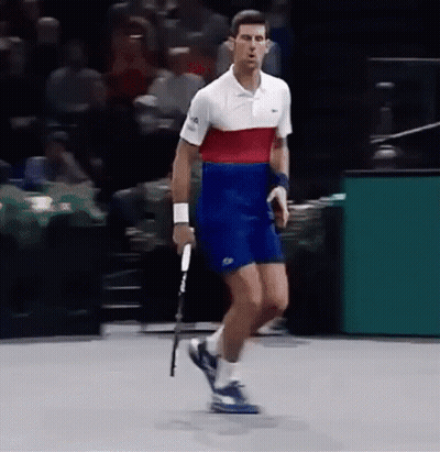 A Man Is Holding A Tennis Racquet On A Court . GIF