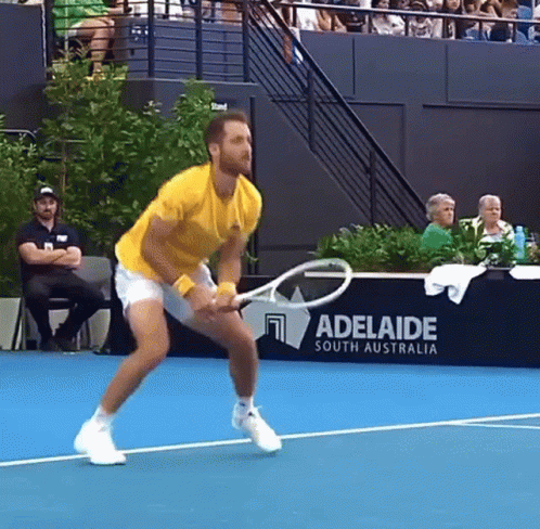 A Man Is Holding A Tennis Racquet On A Tennis Court In Front Of A Adelaide South Australia Sign GIF