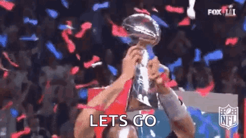 A Man Is Holding A Trophy In His Hands While Confetti Falls Around Him . GIF