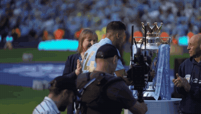 A Man Is Holding A Trophy That Says Premier League On It GIF