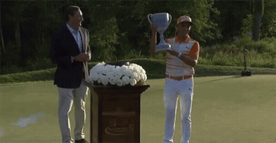A Man Is Holding A Trophy While Standing Next To A Podium With Flowers GIF