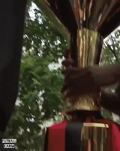 A Man Is Holding A Trophy With The Words Futball Karim Written On The Bottom GIF