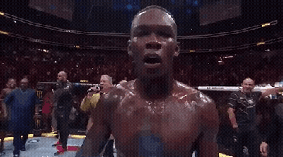 A Man Is Holding A Ufc Heavyweight Championship Belt In Front Of A Crowd Of People . GIF