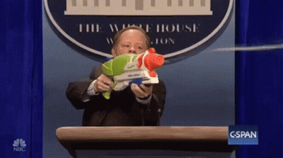 A Man Is Holding A Water Gun In Front Of A White House Logo GIF