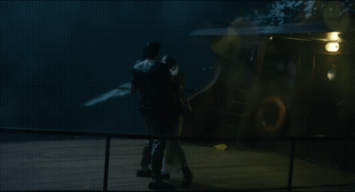 A Man Is Holding A Woman In A White Dress In The Rain GIF