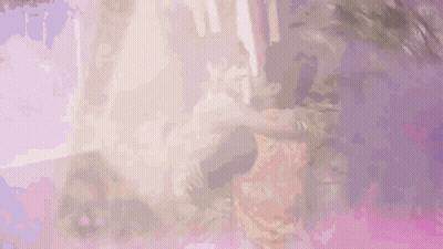 A Man Is Holding A Woman In His Arms And They Are Dancing Together . GIF