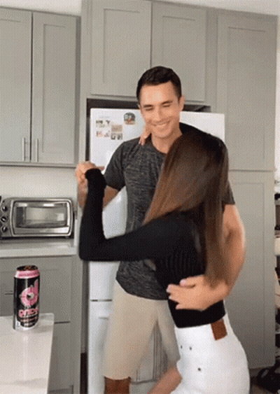 A Man Is Holding A Woman In His Arms In A Kitchen Next To A Can Of Gatorade .. GIF