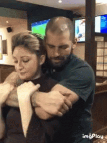 A Man Is Holding A Woman In His Arms In A Restaurant . GIF