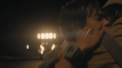 A Man Is Holding A Woman In His Arms In The Dark . GIF