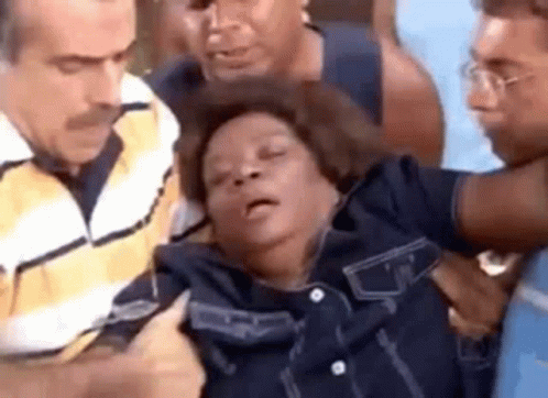 A Man Is Holding A Woman In His Arms While A Group Of People Are Standing Around Her . GIF