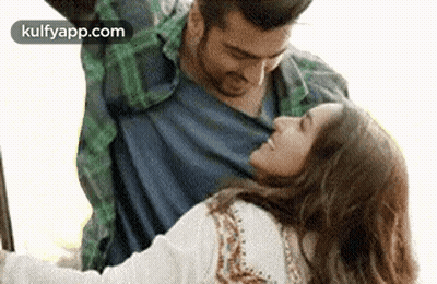 A Man Is Holding A Woman In His Arms While They Are Dancing Together . GIF