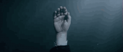 A Man Is Holding A Woman 'S Hand In A Dark Room . GIF