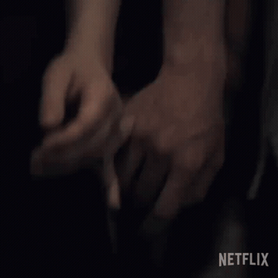 A Man Is Holding A Woman 'S Hand In A Dark Room . GIF