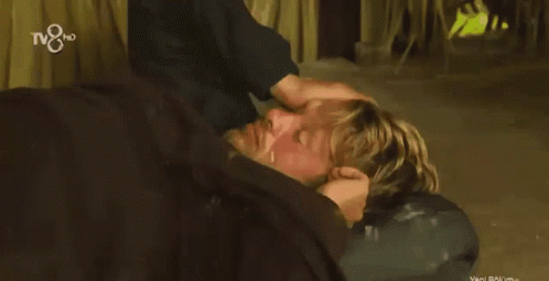 A Man Is Holding A Woman 'S Head While Laying On The Ground With The Tv8 Logo In The Background GIF