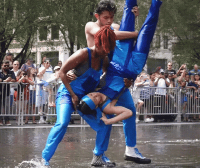 A Man Is Holding A Woman Upside Down In The Air While A Crowd Watches GIF