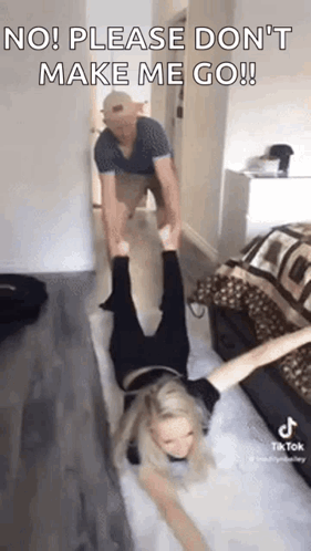 A Man Is Holding A Woman Upside Down On A Yoga Mat In A Living Room . GIF