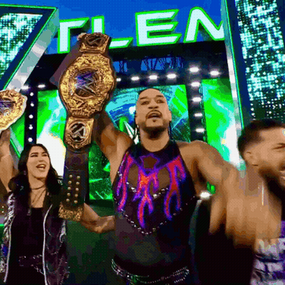 A Man Is Holding A Wrestling Championship Belt In Front Of A Sign That Says " T-Len " GIF
