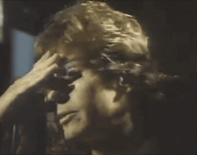 A Man Is Holding His Hand To His Forehead . GIF