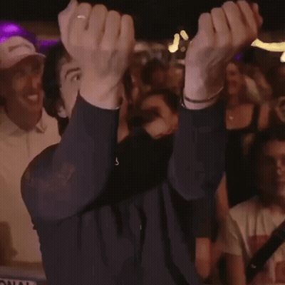A Man Is Holding His Hands Up In The Air While A Crowd Watches GIF
