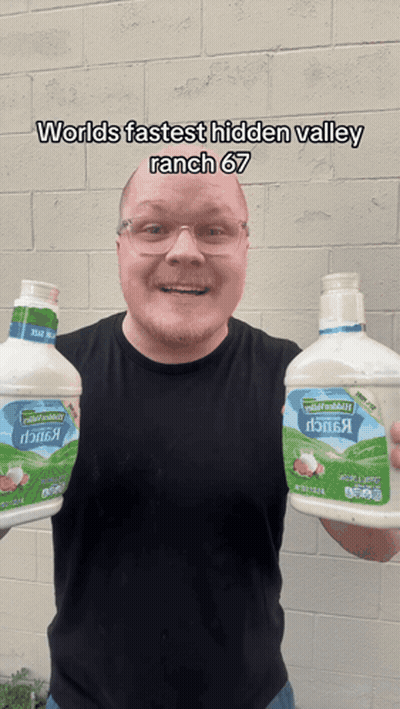 A Man Is Holding Two Bottles Of Ranch Dressing GIF
