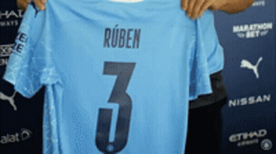 A Man Is Holding Up A Light Blue Jersey With The Number 3 On It GIF