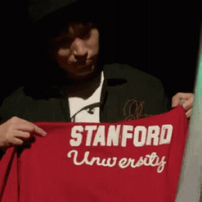 A Man Is Holding Up A Red Stanford University Shirt GIF