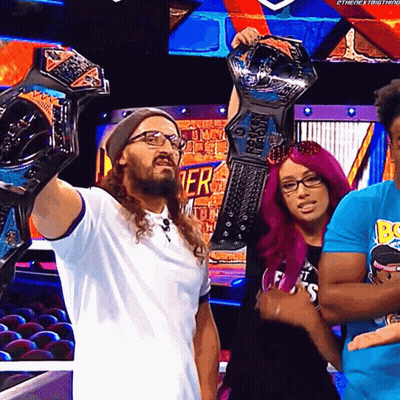 A Man Is Holding Up A Wrestling Championship While Standing Next To A Woman With Pink Hair GIF
