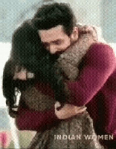 A Man Is Hugging A Woman In A Living Room . GIF