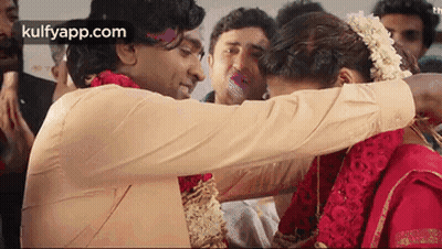 A Man Is Hugging A Woman In A Red Dress . GIF